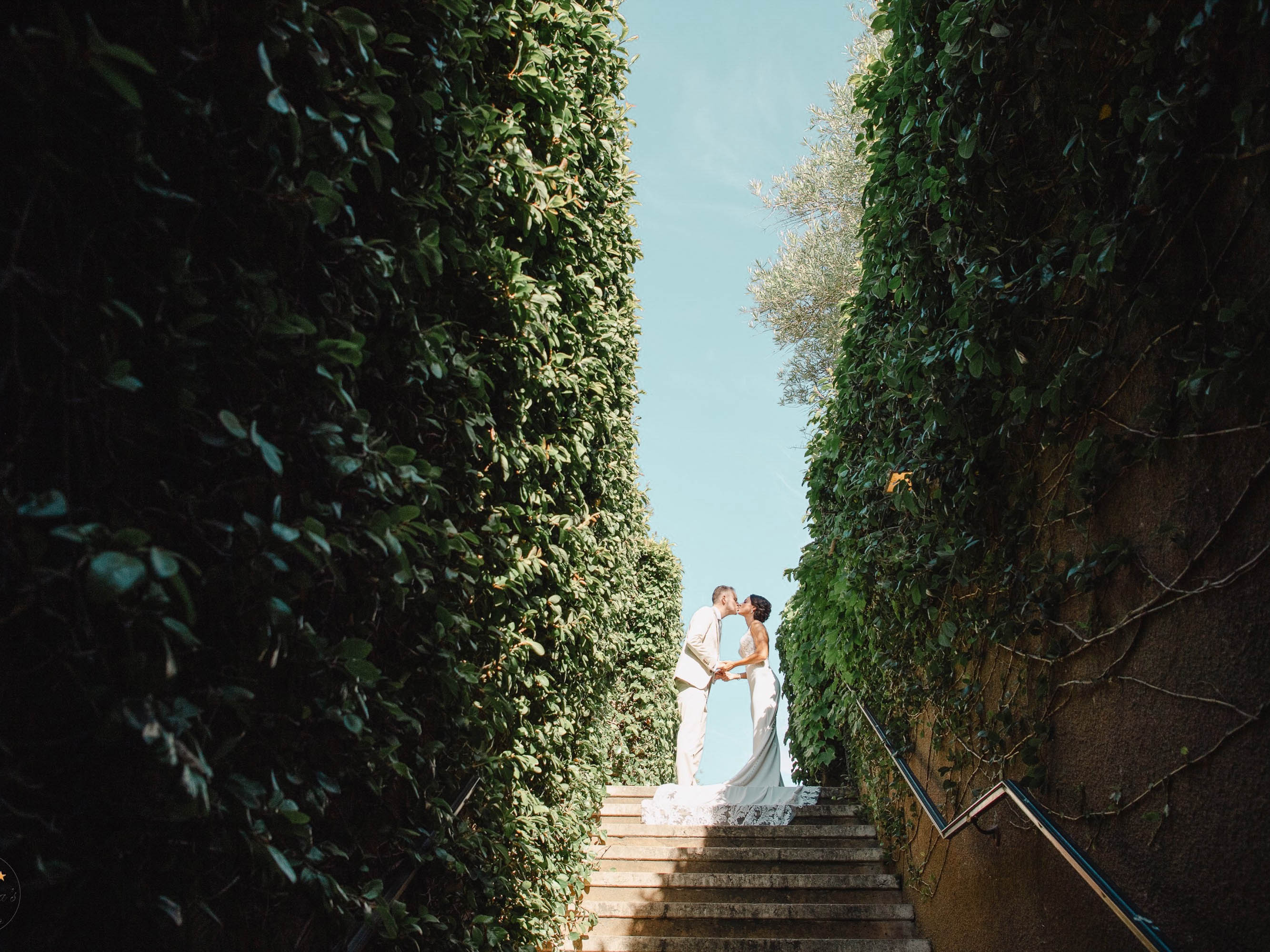 A bride and groom standing on the steps of a garden.