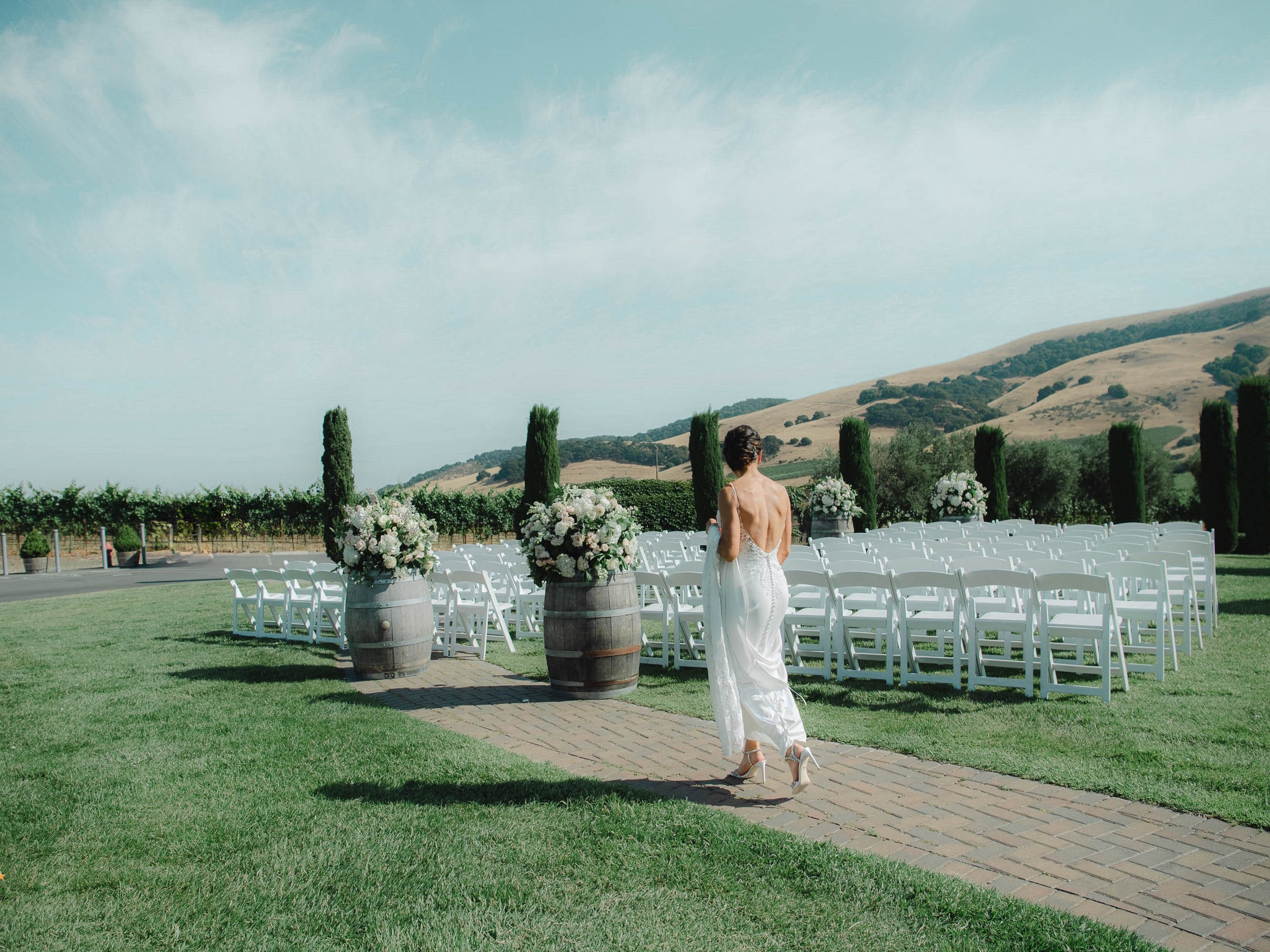 A bride walks down the aisle at a vineyard wedding.