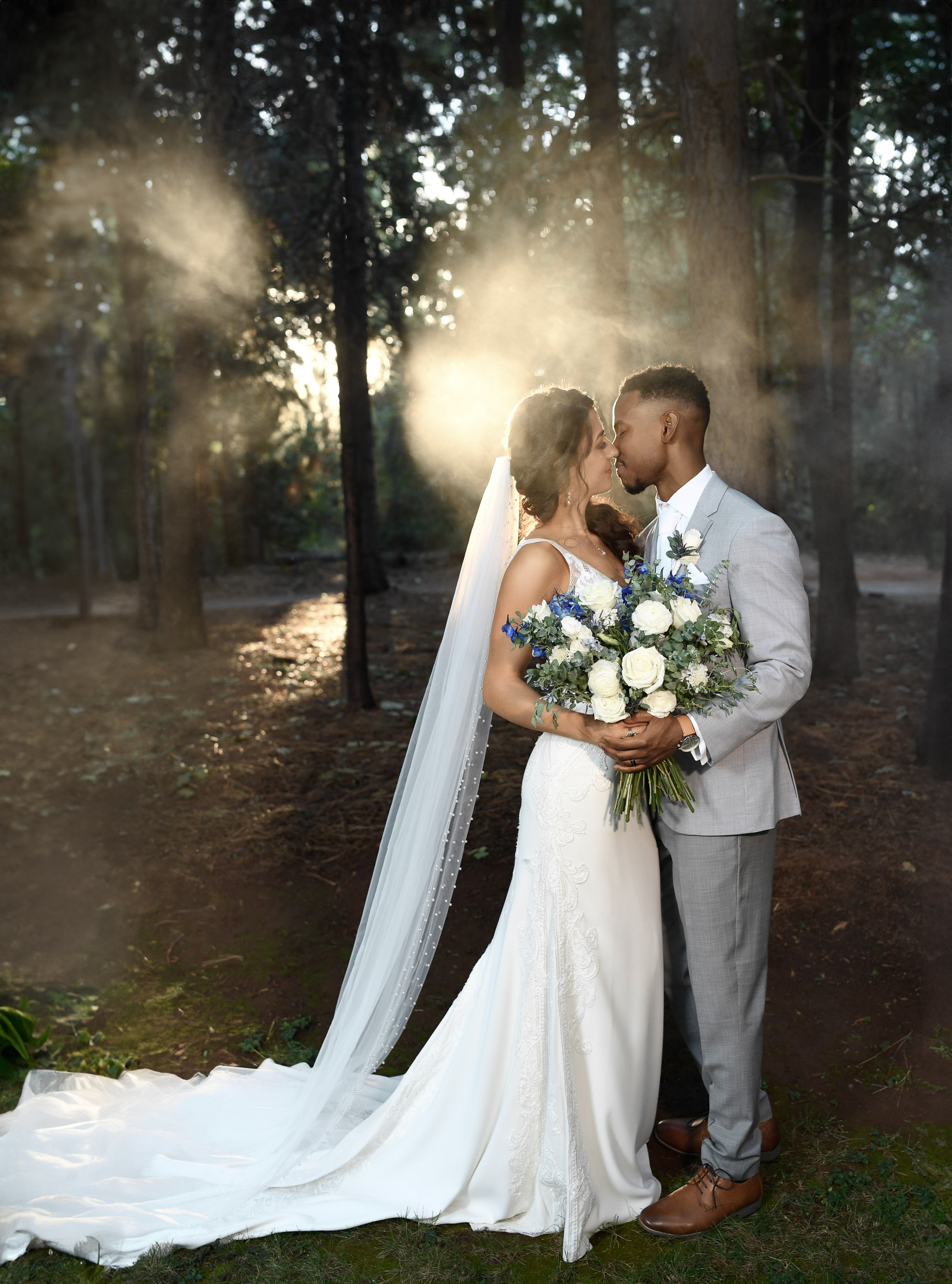 A bride and groom kissing in the woods.