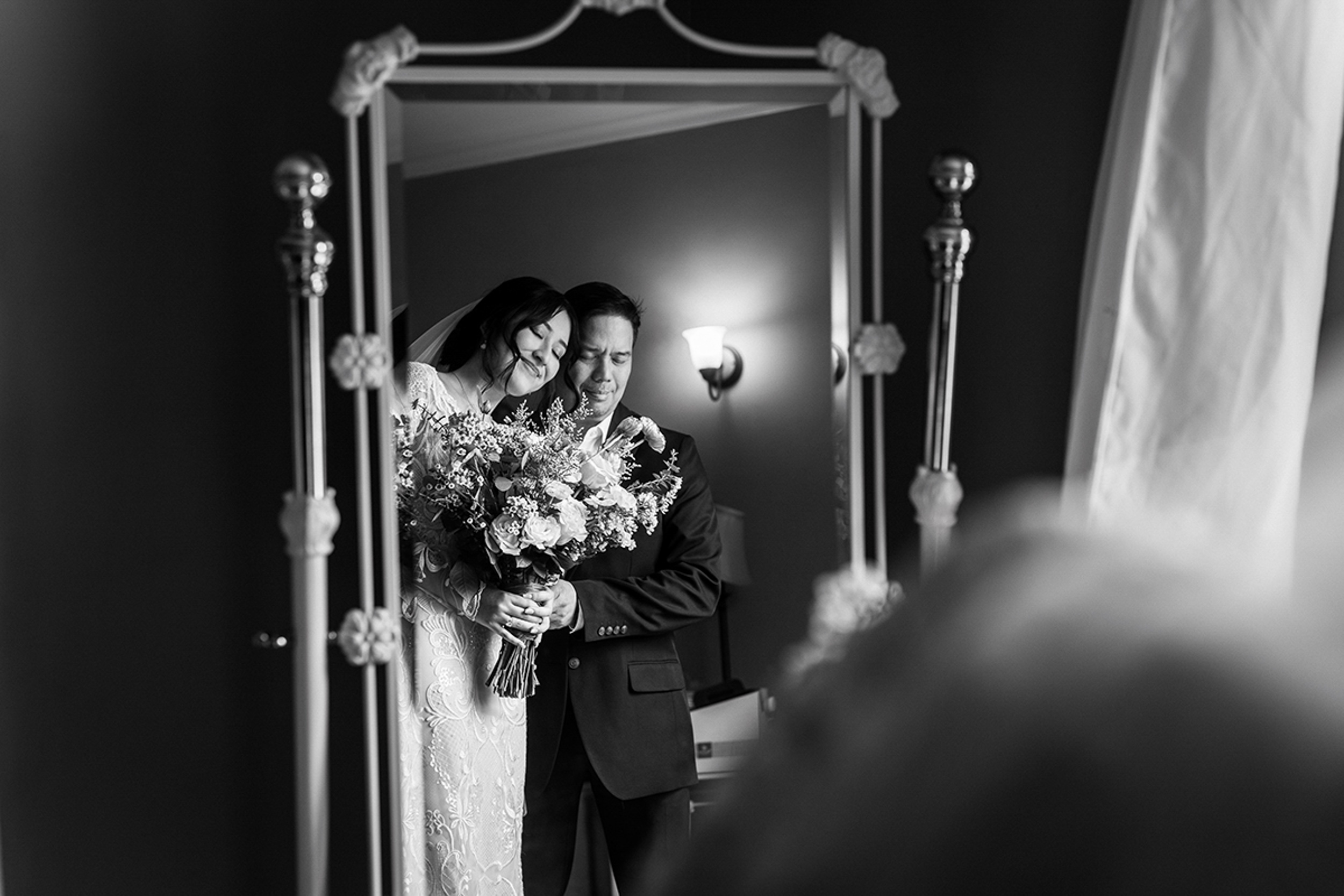 A bride and dad standing in front of a mirror.