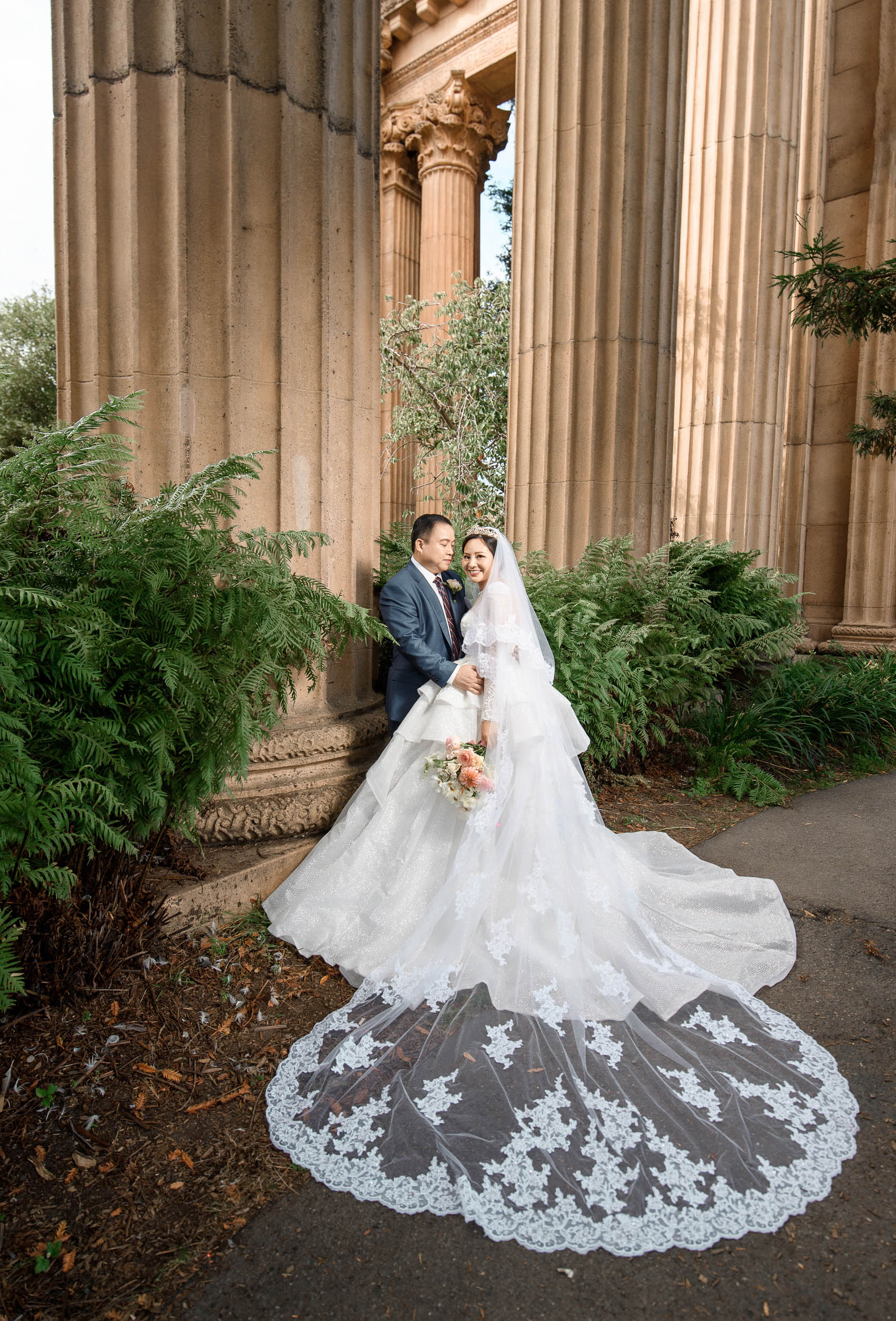 A bride and groom pose in front of pillars at the palace of fine arts.