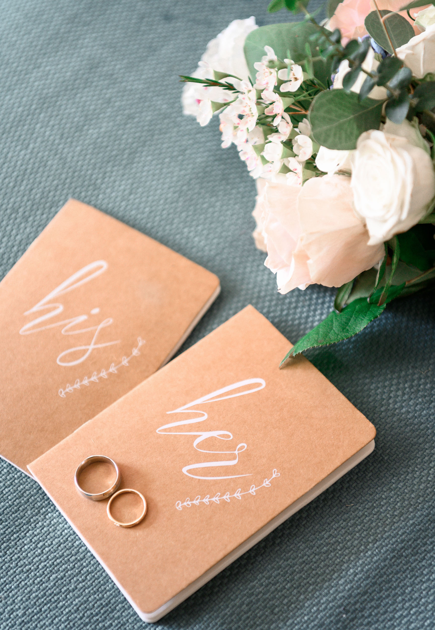 Two wedding rings and a notebook on a table.