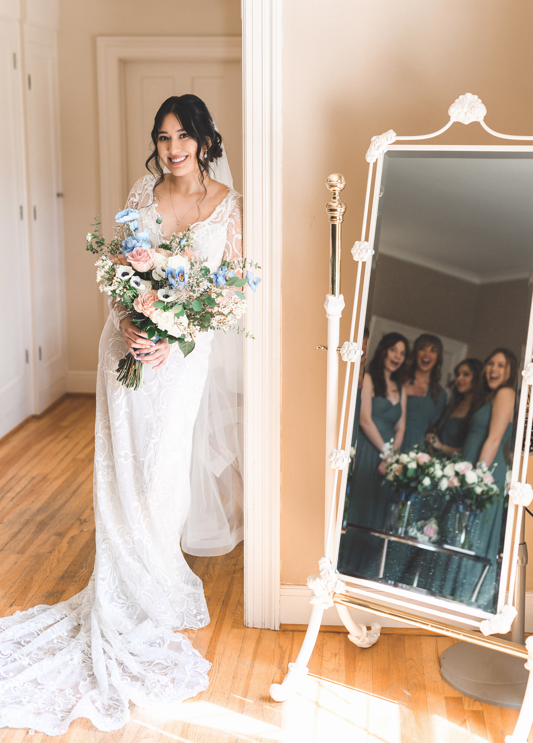A bride and her bridesmaids standing in front of a mirror.