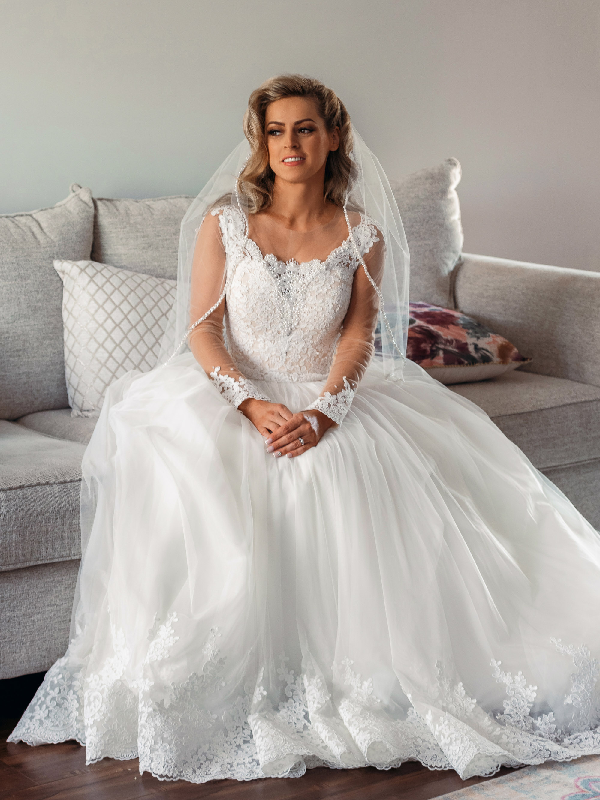 A bride in a wedding dress sitting on a couch.