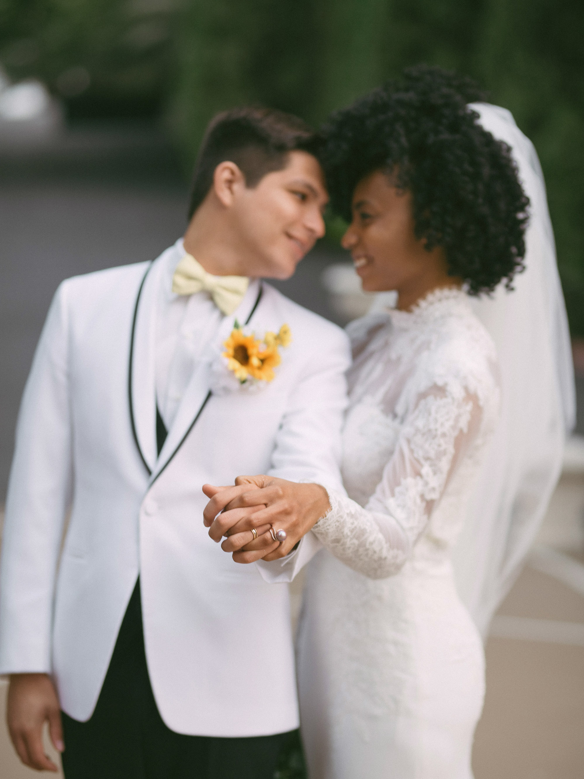 A bride and groom in a white tuxedo holding hands.