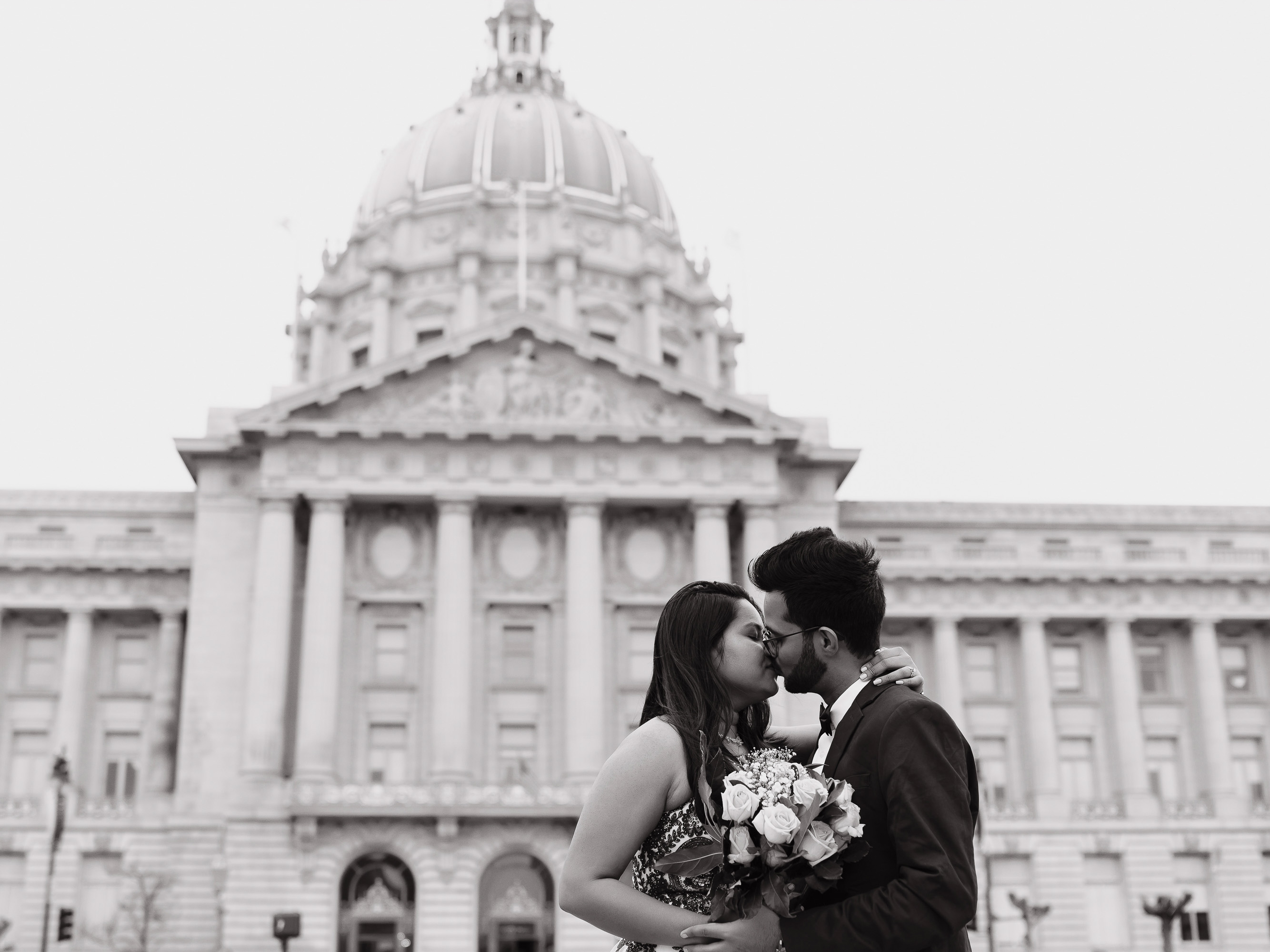 A couple kissing in front of the city hall.